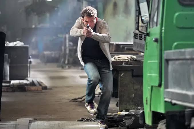 Kriminalista míří zbraní v průmyslové hale